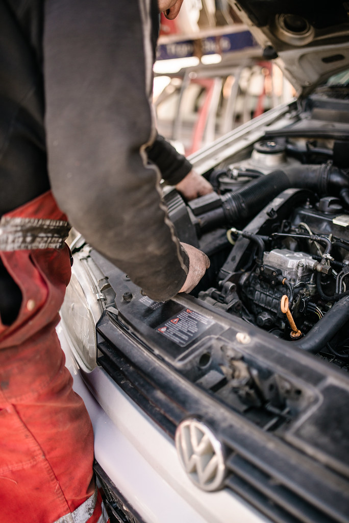 Mechaniker prüft Bauteile in einem geöffneten Motorraum